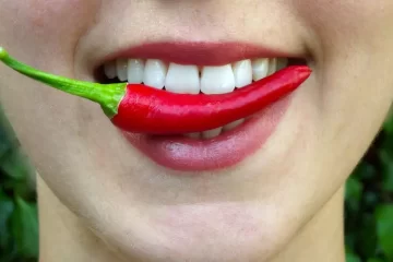 Mulher segurando pimenta nos labios